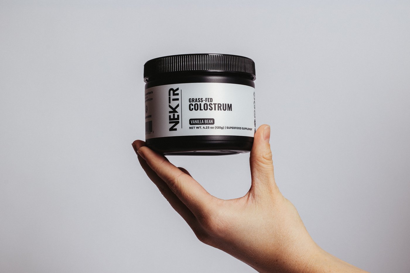 NEKTR Colostrum — hand holding jar