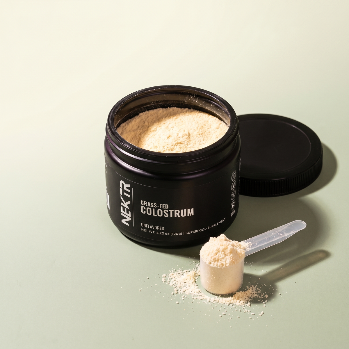 NEKTR Grass-Fed Colostrum — golden powder in open jar with scoop